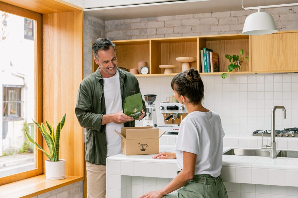 Man and woman in kitchen opening box of coffee